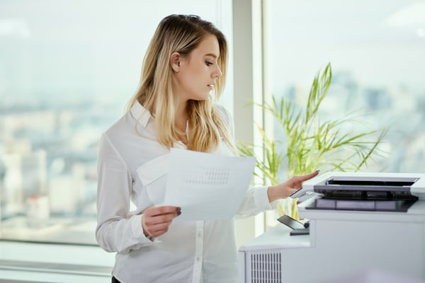 An office worker getting print outs from a copy machine.