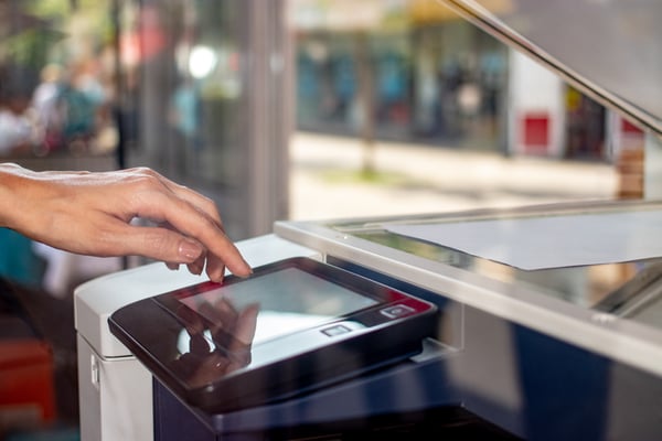 An office worker press a button on a copy machine.