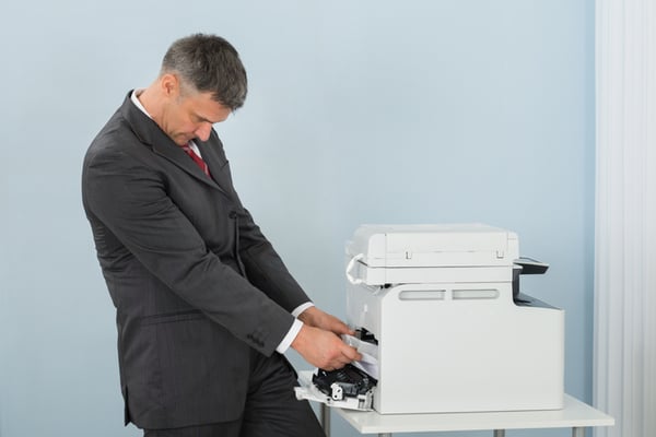 A man trying to fix a paper jam